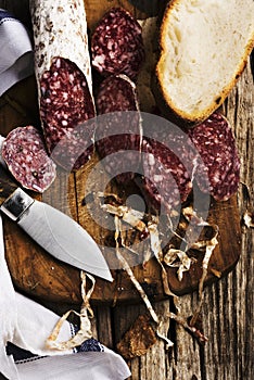 Sliced Ã¢â¬â¹Ã¢â¬â¹salami on wooden cutting board with knife photo